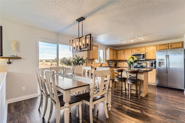 dining space featuring dark wood-style floors, a textured ceiling, a notable chandelier, and baseboards