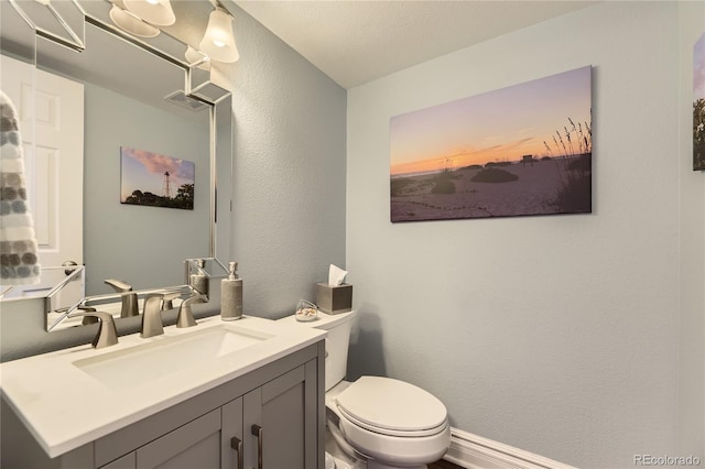 bathroom featuring visible vents, a textured wall, vanity, and toilet