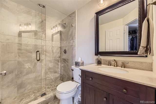 bathroom with toilet, a stall shower, and vanity