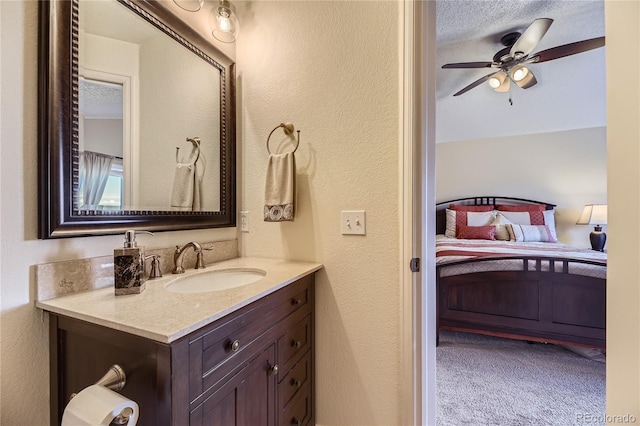 ensuite bathroom with a textured wall, ceiling fan, ensuite bathroom, a textured ceiling, and vanity