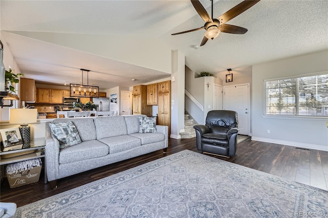 living room with a textured ceiling, dark wood-type flooring, baseboards, stairs, and vaulted ceiling