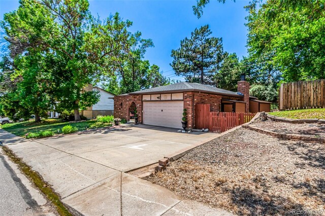 9861 Pecos St, Thornton, CO 80260 - view of property exterior featuring a garage, brick siding, driveway, and a chimney