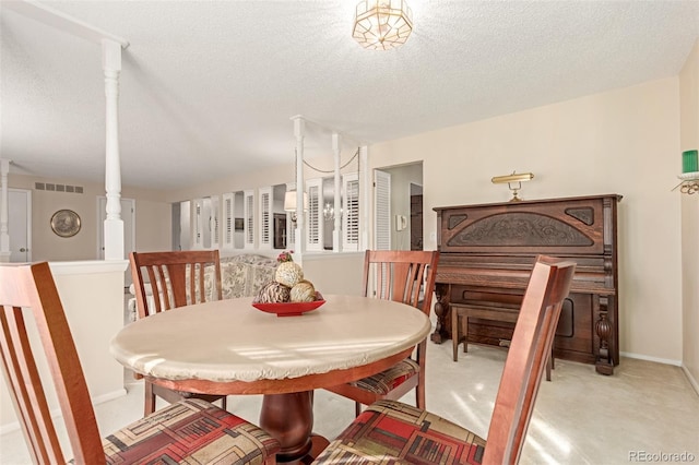 dining area with a textured ceiling, light colored carpet, and a notable chandelier