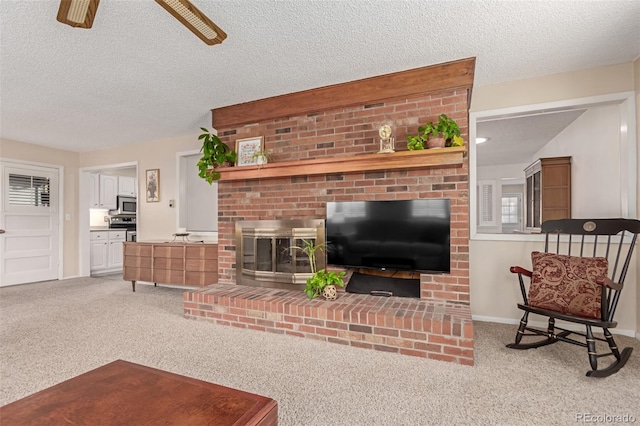 carpeted living room with a brick fireplace, a textured ceiling, and ceiling fan