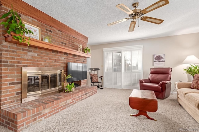 living room with a brick fireplace, a textured ceiling, ceiling fan, and carpet flooring