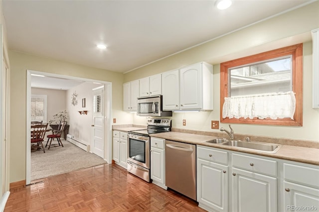 kitchen featuring sink, white cabinetry, light parquet flooring, a baseboard heating unit, and appliances with stainless steel finishes