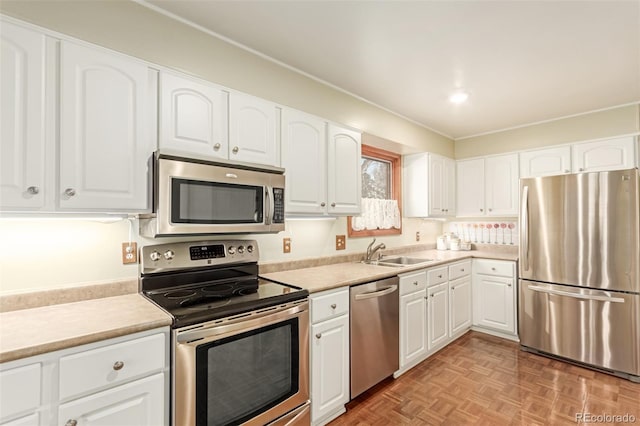 kitchen featuring stainless steel appliances, white cabinetry, sink, and light parquet floors