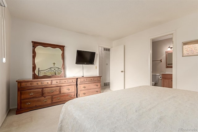 bedroom with ensuite bath and light colored carpet