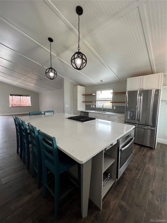 kitchen featuring a healthy amount of sunlight, appliances with stainless steel finishes, open shelves, and dark wood finished floors