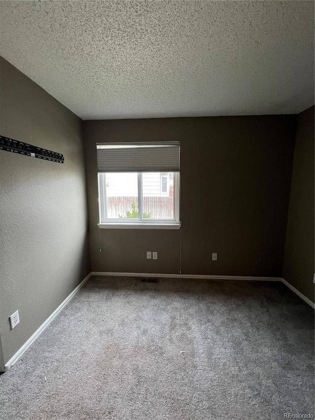 empty room with baseboards, carpet flooring, a textured ceiling, and visible vents
