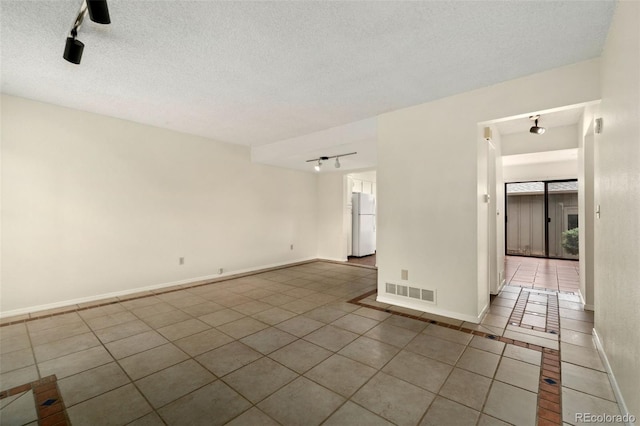 tiled spare room featuring a textured ceiling and rail lighting