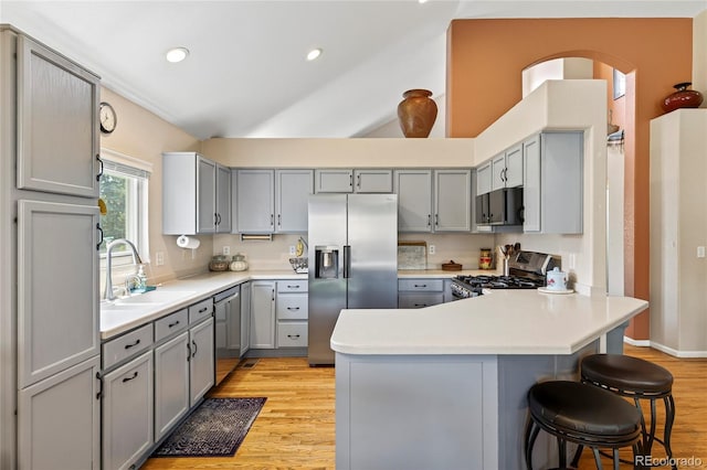 4737 E 127th Ave, Thornton, CO 80241 - kitchen with stainless steel appliances, gray cabinetry, a peninsula, light wood-style flooring, and a breakfast bar area