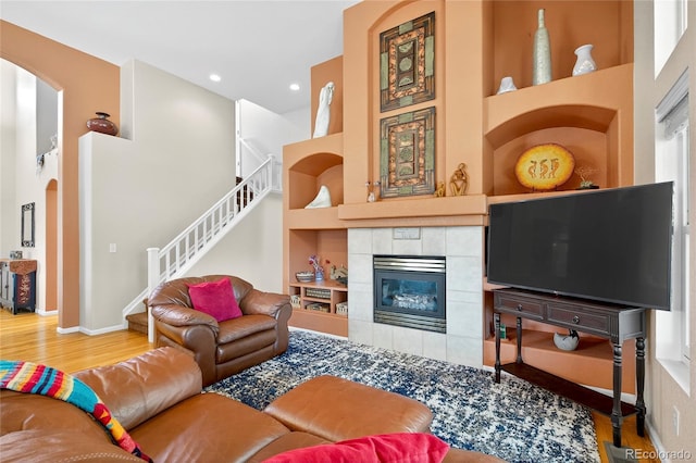4737 E 127th Ave, Thornton, CO 80241 - living room featuring arched walkways, built in shelves, wood finished floors, stairs, and a tile fireplace