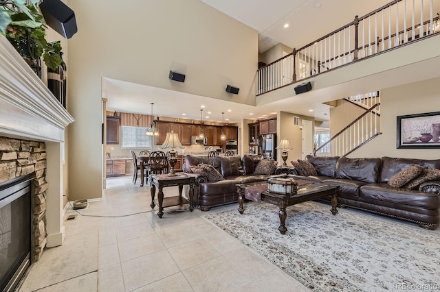 living area featuring light tile patterned floors, baseboards, stairs, a high ceiling, and a fireplace