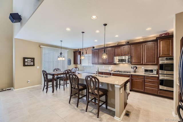 kitchen with stainless steel appliances, visible vents, hanging light fixtures, a sink, and dark brown cabinets