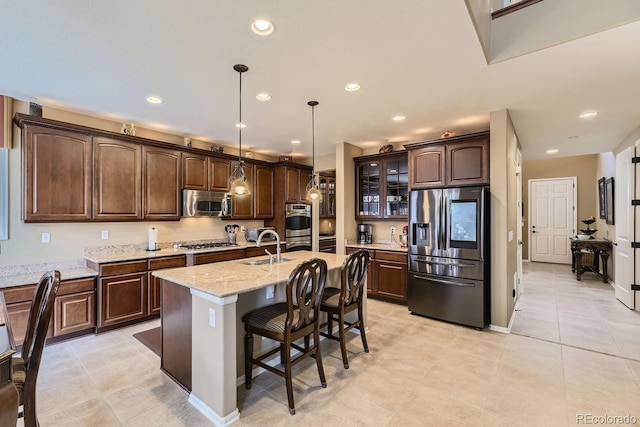 kitchen featuring a breakfast bar, stainless steel appliances, recessed lighting, a sink, and dark brown cabinetry