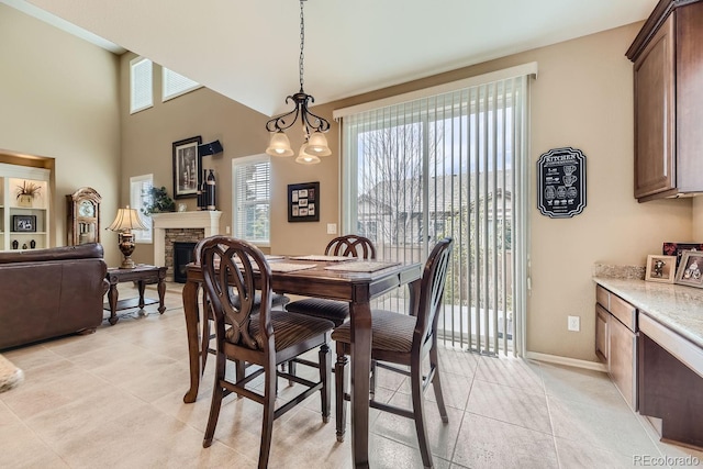 dining room with light tile patterned floors, a fireplace, a chandelier, and baseboards