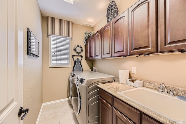 laundry area featuring cabinet space, light tile patterned floors, baseboards, washer and dryer, and a sink