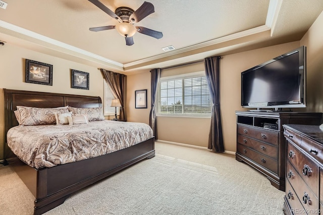 bedroom with a tray ceiling, visible vents, light carpet, and baseboards