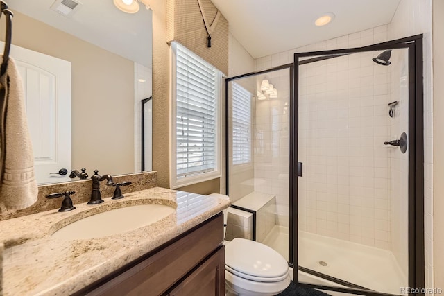 bathroom featuring toilet, vanity, a shower stall, and visible vents