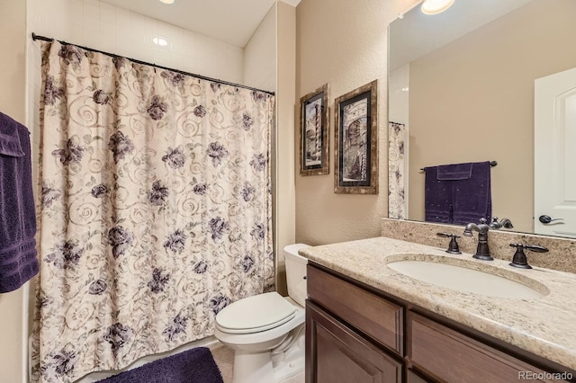 bathroom with toilet, curtained shower, a textured wall, and vanity