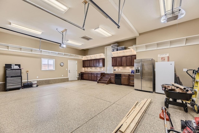 garage with a garage door opener, freestanding refrigerator, and stainless steel fridge with ice dispenser