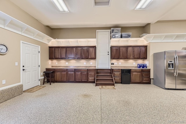 kitchen featuring light countertops, dark brown cabinetry, stainless steel refrigerator with ice dispenser, and baseboards