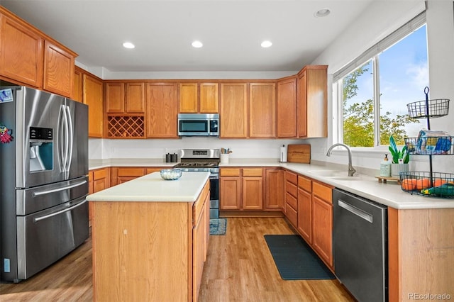 kitchen with appliances with stainless steel finishes, a center island, light hardwood / wood-style floors, and sink