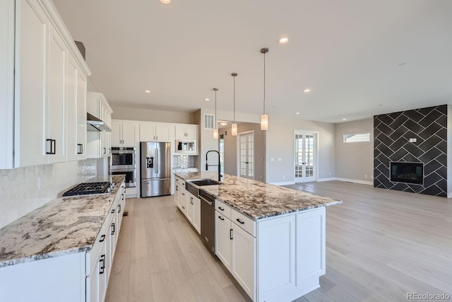 kitchen featuring a spacious island, decorative light fixtures, stainless steel appliances, and white cabinetry