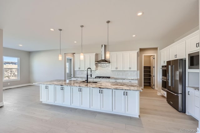 kitchen featuring wall chimney exhaust hood, sink, white cabinets, and stainless steel appliances