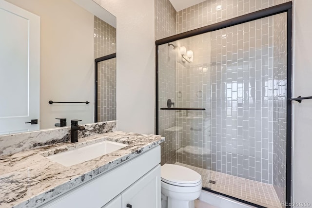 bathroom featuring toilet, a shower with shower door, and vanity