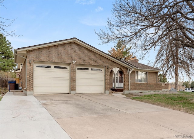 2696 S Yukon Ct, Lakewood, CO 80227 - view of front facade featuring brick siding, driveway, a garage, and a chimney