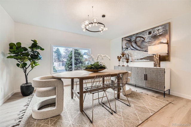 dining area featuring a chandelier, light wood finished floors, and baseboards