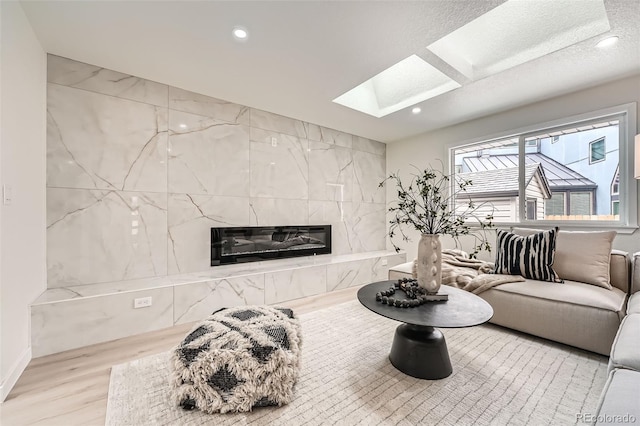 living area featuring a skylight, wood finished floors, recessed lighting, and a premium fireplace