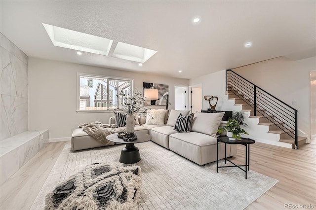 living room with a skylight, light wood-style flooring, stairs, recessed lighting, and baseboards