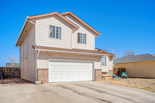 traditional home with driveway, brick siding, an attached garage, and fence