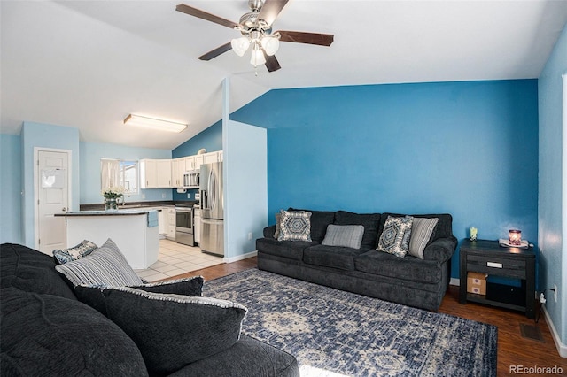 living room with baseboards, visible vents, vaulted ceiling, and a ceiling fan