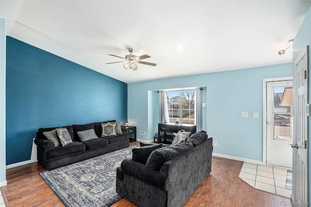 living area featuring a ceiling fan, baseboards, and wood finished floors