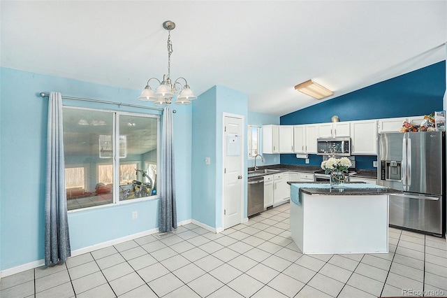 kitchen featuring stainless steel appliances, a sink, white cabinets, vaulted ceiling, and dark countertops