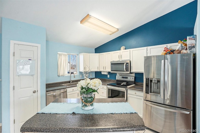 kitchen with appliances with stainless steel finishes, dark countertops, a sink, and white cabinets