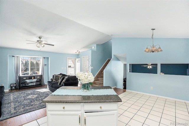 kitchen featuring pendant lighting, lofted ceiling, open floor plan, white cabinetry, and ceiling fan with notable chandelier