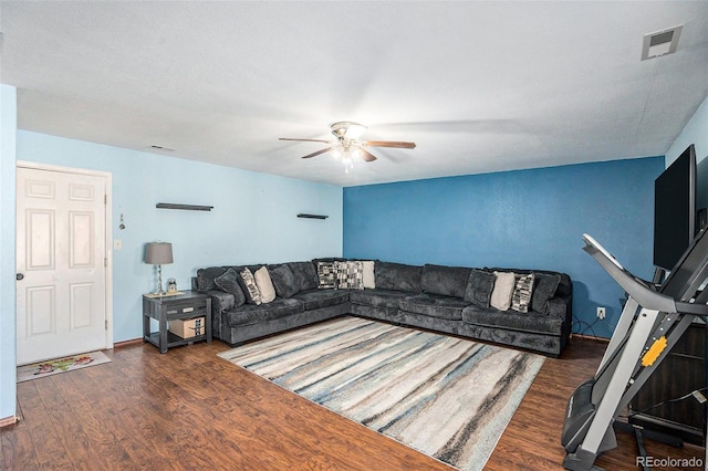 living room with a ceiling fan, visible vents, baseboards, and wood finished floors