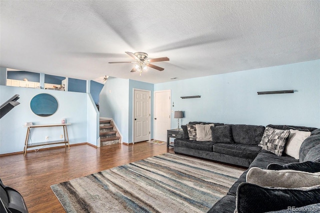 living area featuring stairway, a ceiling fan, a textured ceiling, wood finished floors, and baseboards