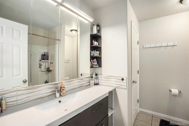 full bathroom with baseboards, toilet, tile patterned floors, walk in shower, and vanity