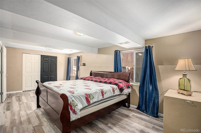 bedroom with baseboards, a closet, visible vents, and wood finished floors