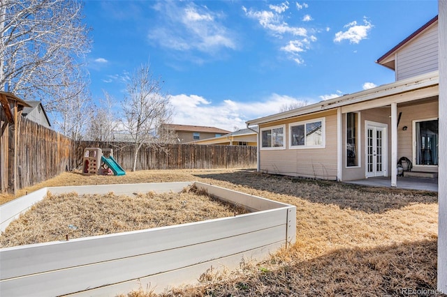 view of yard featuring a patio, french doors, a playground, and a fenced backyard