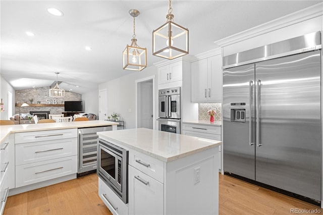 6795 E Kettle Ave, Centennial, CO 80112 - kitchen with built in appliances, lofted ceiling, light wood finished floors, open floor plan, and a stone fireplace