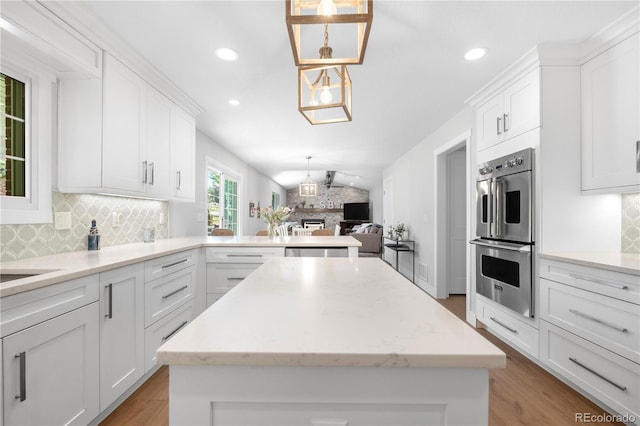 6795 E Kettle Ave, Centennial, CO 80112 - kitchen featuring appliances with stainless steel finishes, backsplash, a center island, light wood-style flooring, and recessed lighting
