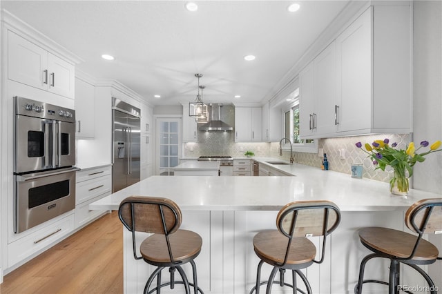 6795 E Kettle Ave, Centennial, CO 80112 - kitchen featuring stainless steel appliances, wall chimney exhaust hood, light countertops, recessed lighting, and white cabinetry