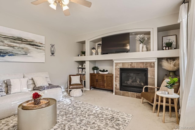 living room featuring ceiling fan, carpet, and a tiled fireplace